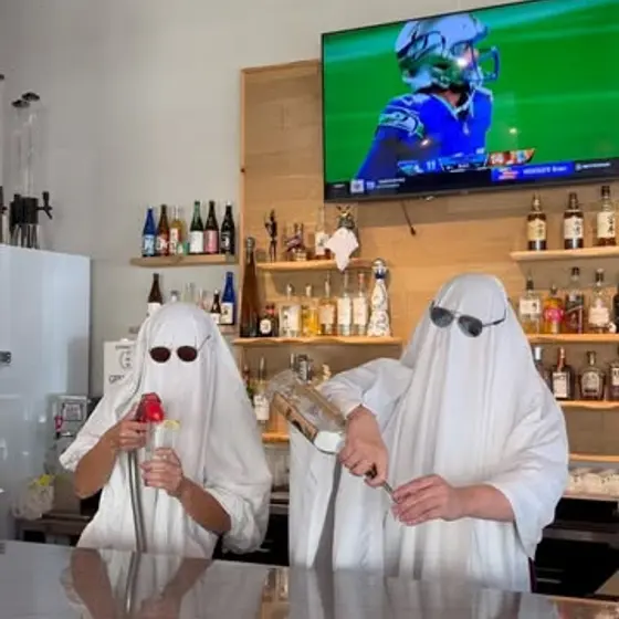 Two bartenders in ghost costumes and sunglasses behind the Curry Tei bar.