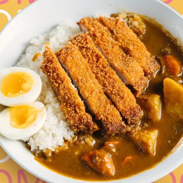 Crispy pork katsu sliced over rice and Japanese curry with potatoes and carrots, with a soft-boiled egg.
